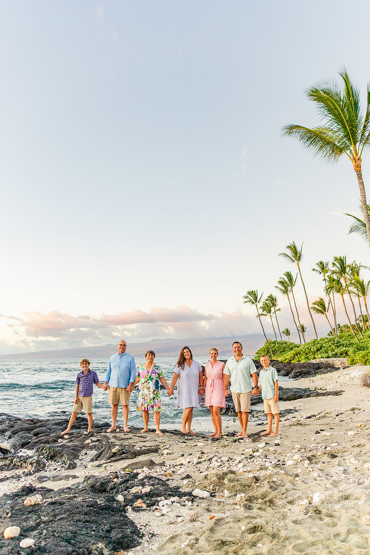 Family laughing together during a sunset beach photoshoot at Mauna Lani